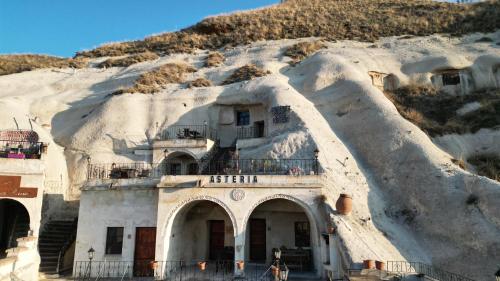 a building on a snow covered hill with a mountain at Asteria Cave Hotel in Goreme