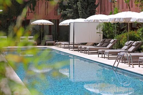 a swimming pool with lounge chairs and umbrellas at Kenzi Club Agdal Medina - All Inclusive in Marrakesh