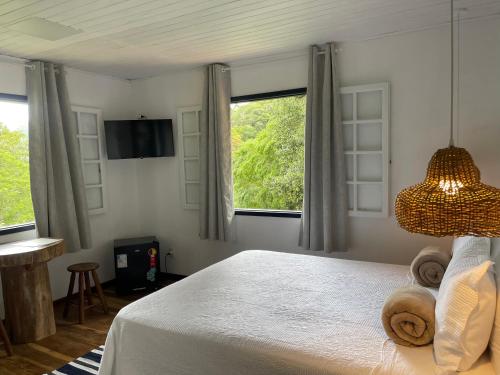 a bedroom with a white bed and a window at Sítio Flor das Águas in Lumiar