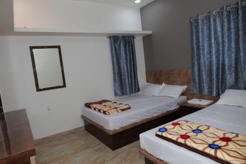 a hotel room with two beds and a mirror at Shree Jyotirlinga Residency in Ellora