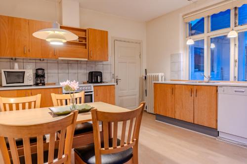 a kitchen with a wooden table and chairs and a kitchen with a counter at Villa Apartments Viborg in Viborg
