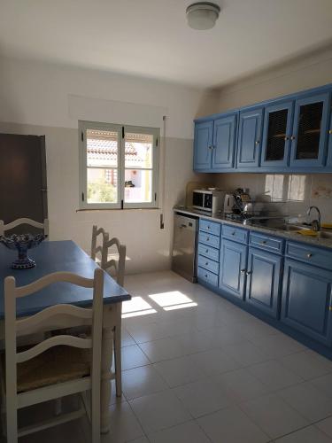 a kitchen with blue cabinets and a table and chairs at Casa da Alzira T2 in Vila Nova de Milfontes
