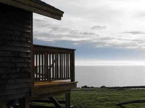 a deck on the side of a house overlooking the ocean at Chalets Nature Océan in Perce