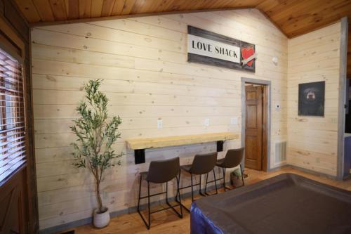 a room with a wooden wall with a bar and stools at Love Shack in Sevierville
