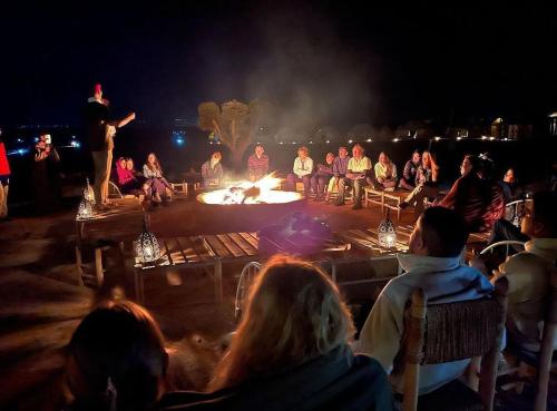 a group of people sitting around a fire pit at Dar Inacamp in El Mjed