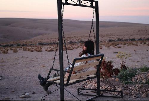 a woman sitting on a swing in the desert at Dar Inacamp in El Mjed