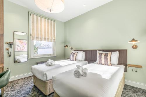 a hotel room with two beds and a mirror at Clapham Guest House in London