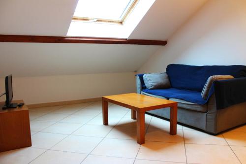 a living room with a blue couch and a table at La Bullote - Gîtes - Paris Roissy CDG in Villeneuve-sous-Dammartin