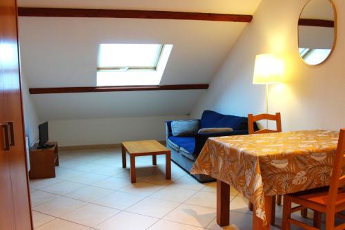 a living room with a table and a blue couch at La Bullote - Gîtes - Paris Roissy CDG in Villeneuve-sous-Dammartin