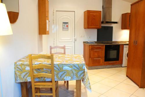a kitchen with a table and two chairs and a kitchen with a stove at La Bullote - Gîtes - Paris Roissy CDG in Villeneuve-sous-Dammartin