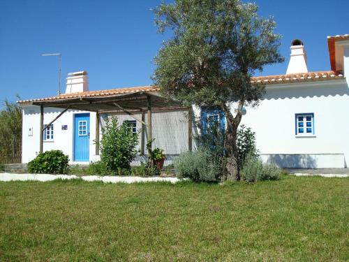 a white house with a tree in front of it at Monte da Pereira - Casa Rural em Espaço Tranquilo in Vila Nova de Milfontes
