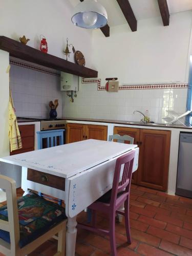 a kitchen with a white table and some chairs at Monte da Pereira - Casa Rural em Espaço Tranquilo in Vila Nova de Milfontes