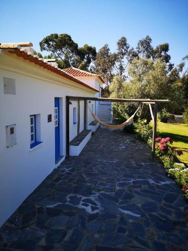 a patio with a hammock next to a house at Monte da Pereira - Casa Rural em Espaço Tranquilo in Vila Nova de Milfontes
