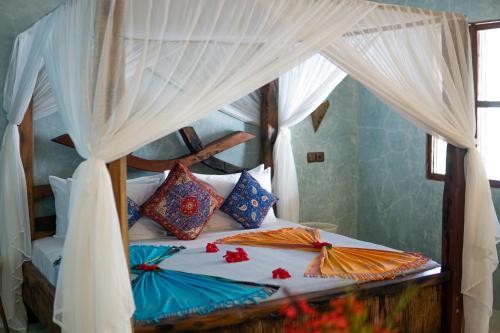 a bedroom with a canopy bed with colorful pillows at Casa Paradis Boutique Hotel in Jambiani