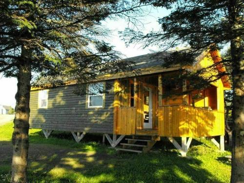 a tiny house sitting in the grass near some trees at Chalets Nature Océan in Perce