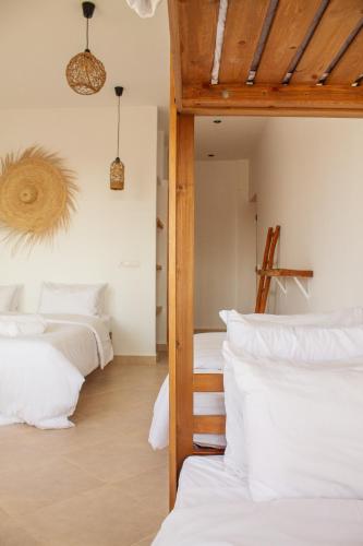 a bedroom with four beds with white pillows at Monza Surf House in Tamraght Ouzdar