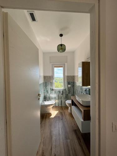 a bathroom with a sink and a toilet and a window at COZY ALBA apartment in Sasso dʼOmbrone