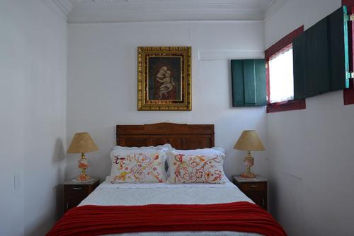 a bedroom with a bed with two lamps and a picture on the wall at Pousada Guignard in Ouro Preto
