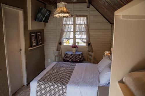 a bedroom with a bed in a room with a window at Pousada Caliandra Da Serra in Canela