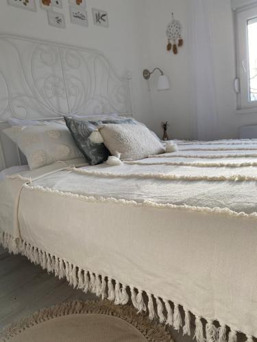 a white bed with white sheets and pillows on it at Vikendica Fruška lipa in Čortanovci