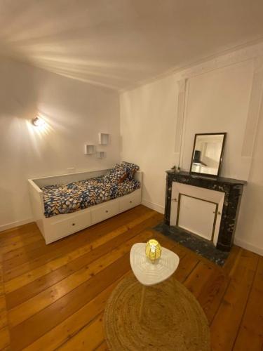 Cette chambre comprend un lit, une table et une cheminée. dans l'établissement L'Imprimerie B2, studio cosy au coeur La Roche, à La Roche-sur-Yon