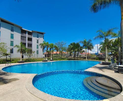 Hermosa Homestay في لاهاد داتو: حمام سباحة مع أشجار النخيل ومبنى