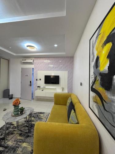 a living room with a yellow couch and a table at Cozy one bedroom apartment in Abuja