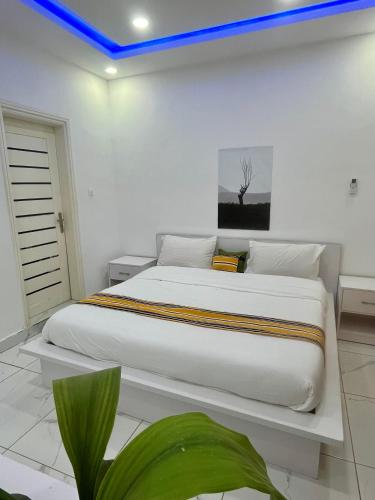 a white bedroom with a large bed with a blue light at Résidence Turpin in Toubab Dialaw