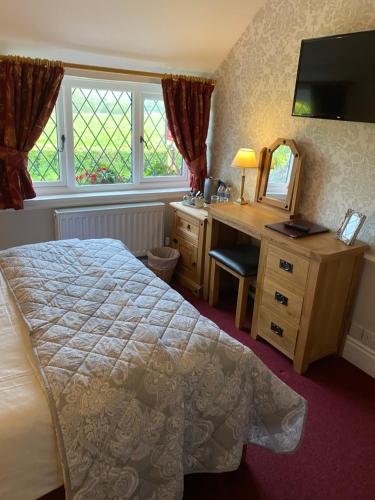 a bedroom with a bed and a desk and a mirror at Greyhound Country Inn in Honiton