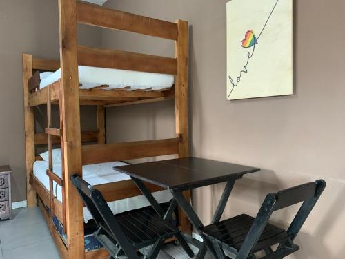a table and two chairs next to a bunk bed at Chapéu de Sol - Área Gourmet, TV, Internet, Roupas de Cama e Banho, Jardim, Horta e Pomar in Ilha Comprida