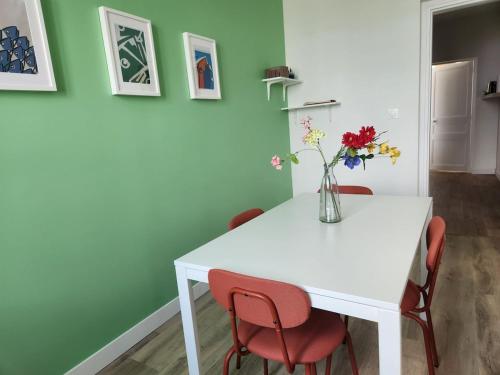 a white table with red chairs and a vase of flowers at 3- Vue sur le port, la ville close, confort, WIFI in Concarneau