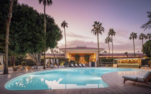 a swimming pool in front of a house with palm trees at The Scott Resort & Spa in Scottsdale