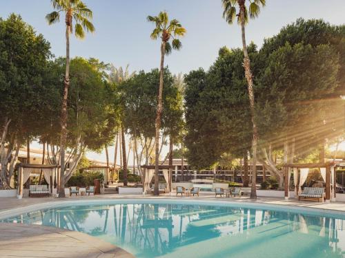 a swimming pool with palm trees in the background at The Scott Resort & Spa in Scottsdale