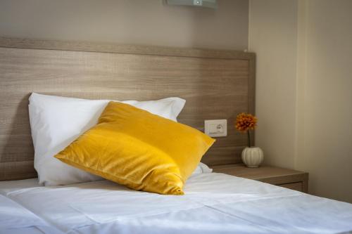 a yellow pillow sitting on top of a bed at Tuscasì Aparthotel in Sovicille