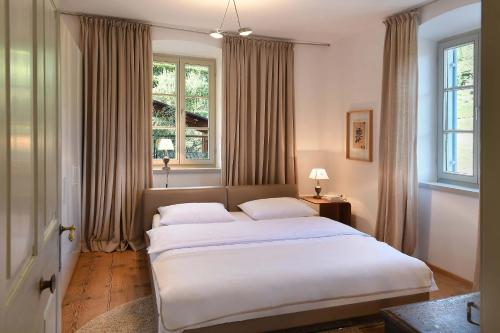 a bedroom with a large bed and two windows at Frühmesserhaus Refugium zu Sanct Kassian in Lagundo