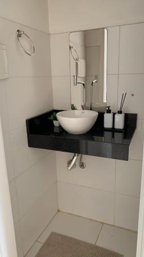 a bathroom with a white sink and a mirror at Aconchegante Apartamento in Porto Seguro