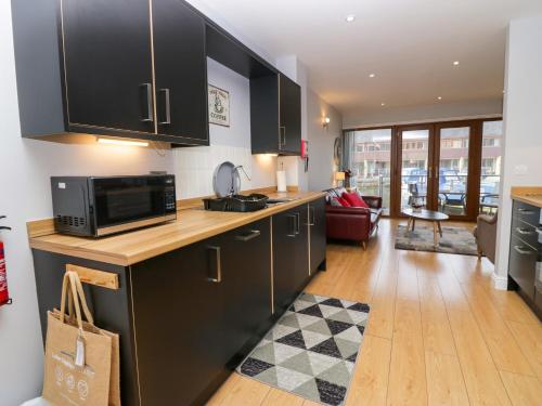 a kitchen with black cabinets and a living room at 9 Swan House in Carnforth