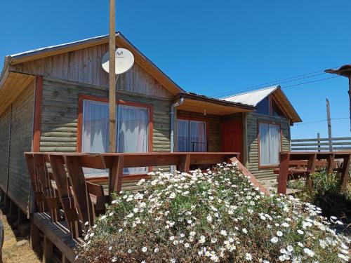 a log cabin with a porch and flowers at Cabaña lagunillas in Matanzas