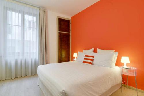 a bedroom with a white bed and an orange wall at Al Cavour 34 in Trento