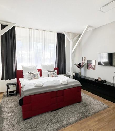 a red bed in a room with a large window at Wohnung im Zentrum von Neuss - Estia Living in Neuss