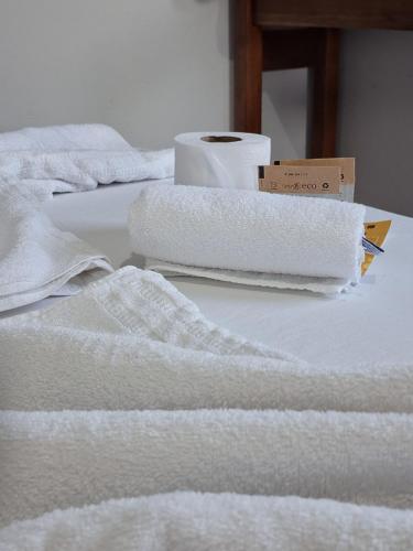 a pile of white towels sitting on a bed at Chapéu de Sol - Área Gourmet, TV, Internet, Roupas de Cama e Banho, Jardim, Horta e Pomar in Ilha Comprida