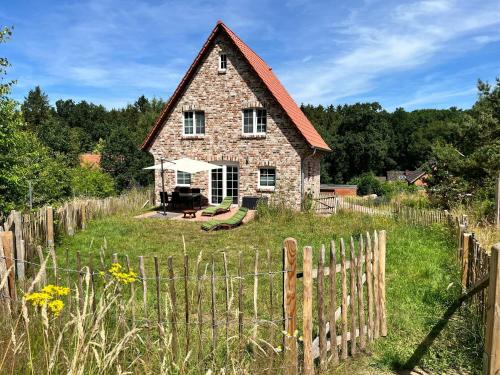 an old stone house in a field with a fence at Bispinger-Heidezauber-Haus-Felsenbirne in Bispingen
