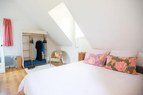 - une chambre avec un lit blanc et des oreillers dans l'établissement Entre Mer et Nature - Bain nordique et sauna, à Clohars-Carnoët