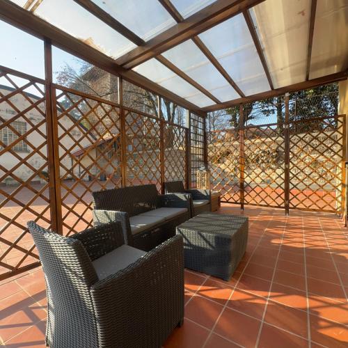 a screened in porch with chairs and tables at Cas'Ale Suites Foresteria Lombarda in Crema