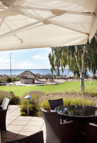 a patio with a table and chairs under a white umbrella at Hotel Faaborg Fjord in Fåborg