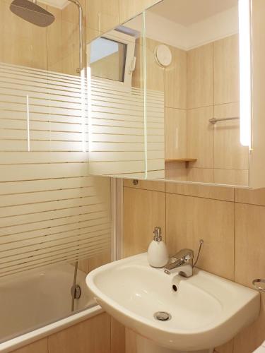 a bathroom with a sink and a mirror and a tub at Sunset Green Apartman in Bük