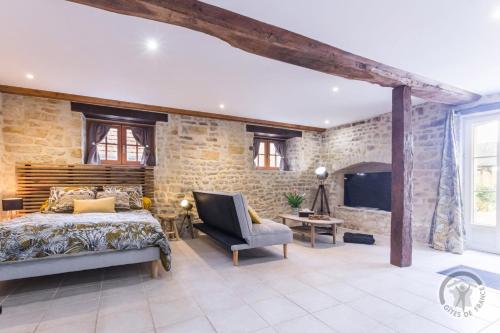 a bedroom with a king sized bed and a stone wall at Le refuge de la fermière in Juaye-Mondaye