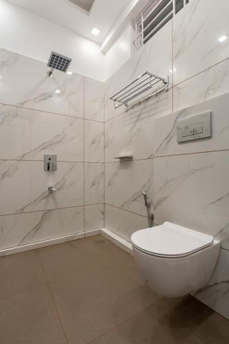 a white bathroom with a toilet and a shower at Cochin Airport Hotel in Ernakulam
