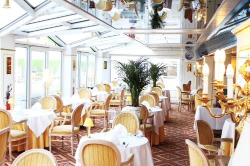 un restaurant avec des tables blanches, des chaises et des fenêtres dans l'établissement Hotel Appartement Landhaus Stutzi - Hotel Strandperle, à Cuxhaven