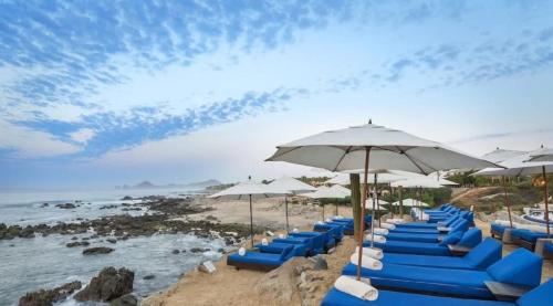 a row of blue chairs and umbrellas on a beach at 4BD Oceanfront Unit Vista Encantada - Cabo in Cabo San Lucas